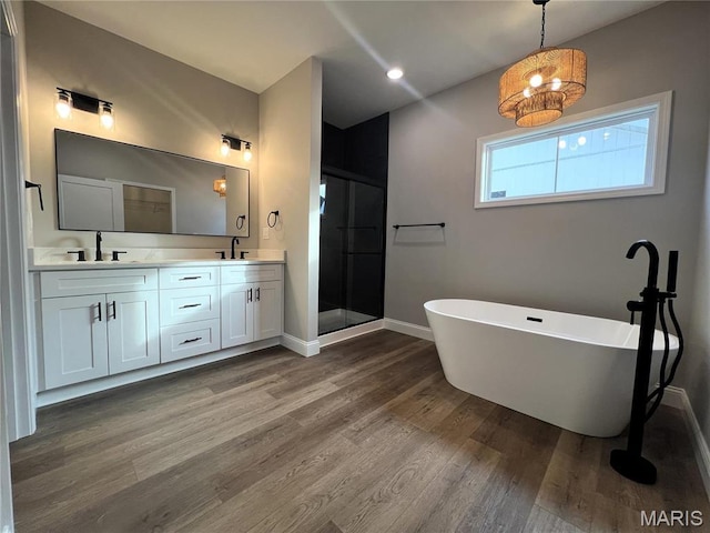 210 Sunny Dr, Rolla, MO 65401 - bathroom featuring baseboards, wood finished floors, a shower stall, double vanity, and a freestanding bath
