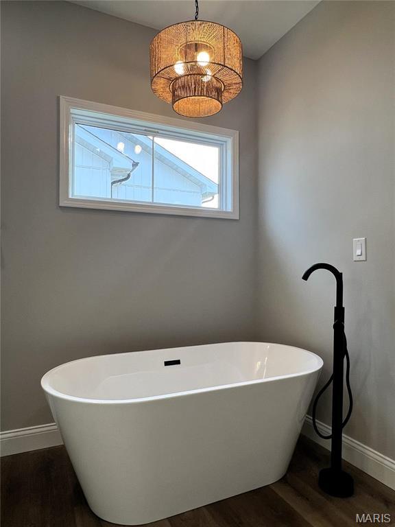 210 Sunny Dr, Rolla, MO 65401 - bathroom with wood finished floors, baseboards, and a freestanding bath