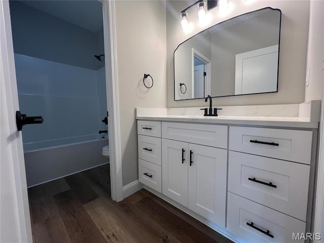 210 Sunny Dr, Rolla, MO 65401 - bathroom featuring wood finished floors, vanity, washtub / shower combination, toilet, and baseboards
