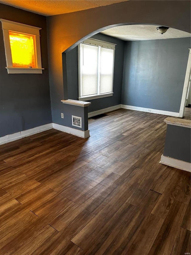 6705 Saint Louis Ave, Saint Louis, MO 63121 - unfurnished room featuring arched walkways, dark wood-style flooring, a textured ceiling, and baseboards