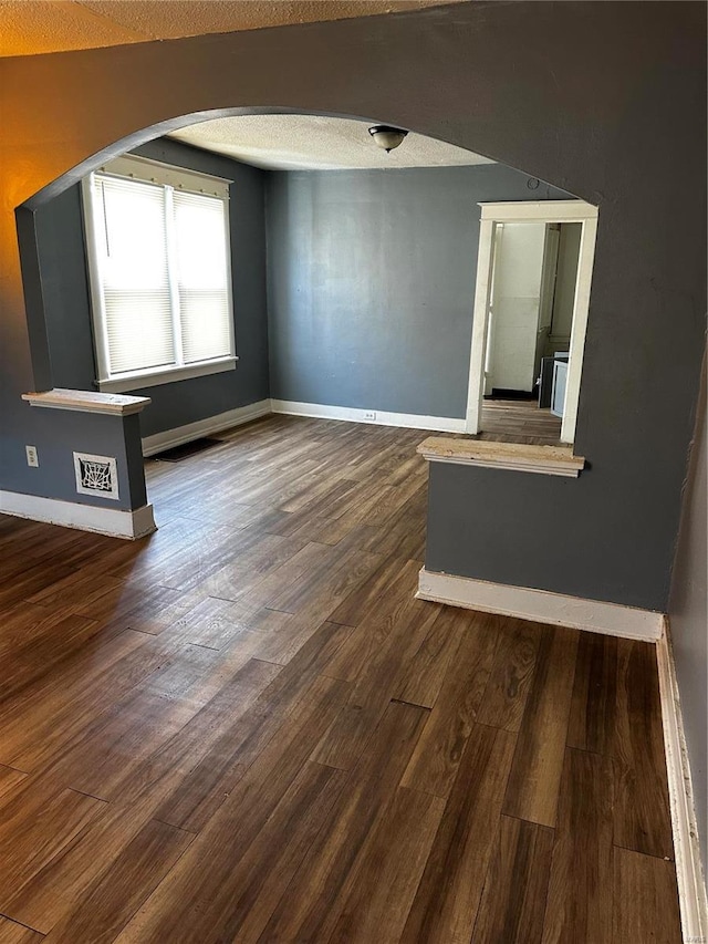 6705 Saint Louis Ave, Saint Louis, MO 63121 - unfurnished room featuring arched walkways, baseboards, wood finished floors, and a textured ceiling