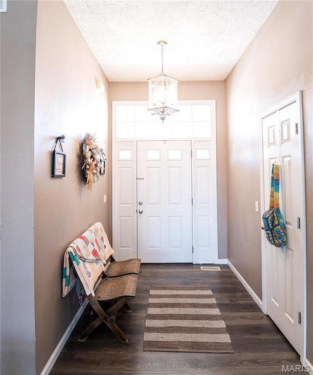 10415 Summerfield Dr, Rolla, MO 65401 - foyer entrance with a chandelier, a textured ceiling, dark wood-type flooring, and baseboards