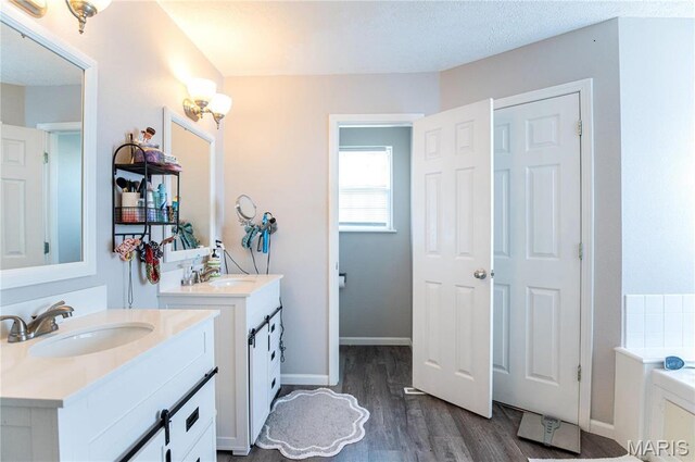 10415 Summerfield Dr, Rolla, MO 65401 - full bathroom featuring wood finished floors, two vanities, a garden tub, and baseboards