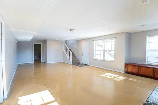 10415 Summerfield Dr, Rolla, MO 65401 - unfurnished living room featuring baseboards, stairs, a textured ceiling, and plenty of natural light
