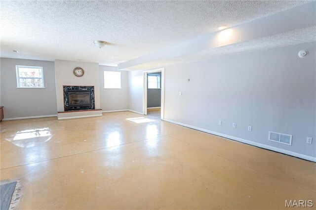 10415 Summerfield Dr, Rolla, MO 65401 - unfurnished living room with a textured ceiling, a high end fireplace, finished concrete flooring, healthy amount of natural light, and baseboards