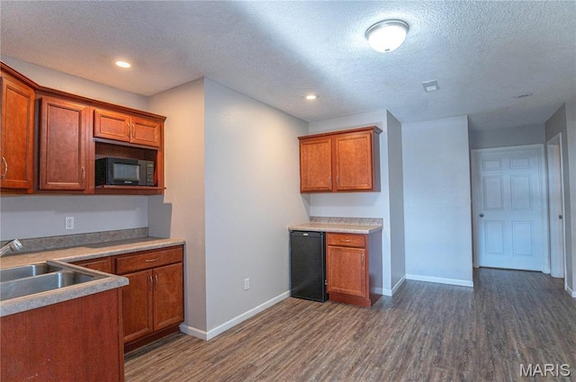 10415 Summerfield Dr, Rolla, MO 65401 - kitchen featuring black microwave, dark wood-style flooring, a sink, brown cabinetry, and a textured ceiling
