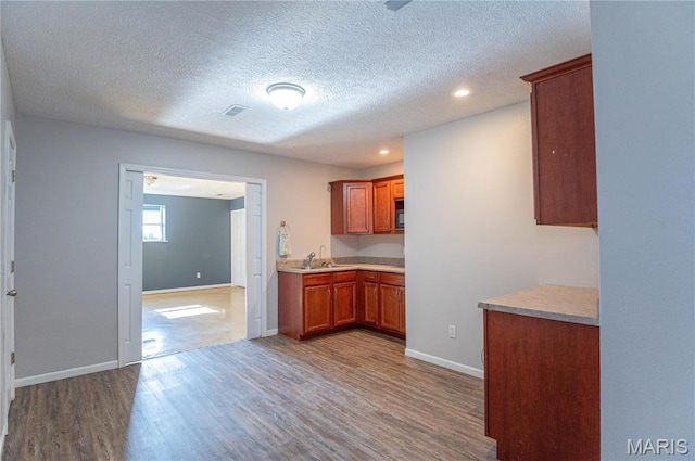 10415 Summerfield Dr, Rolla, MO 65401 - kitchen featuring a sink, wood finished floors, light countertops, brown cabinets, and a textured ceiling