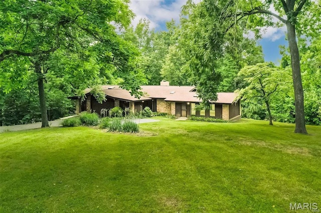 rear view of house featuring a lawn and a chimney