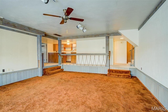 home theater room with carpet floors, a ceiling fan, and a wainscoted wall