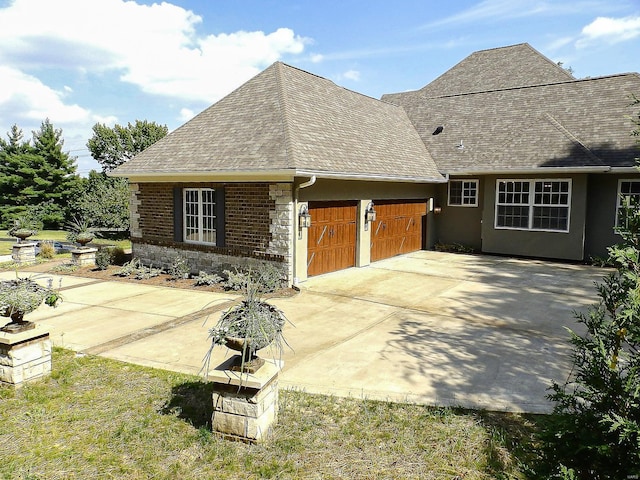 267 Saint Andrews Dr, Saint Albans, MO 63073 - view of side of home featuring roof with shingles, a garage, stone siding, stucco siding, and driveway