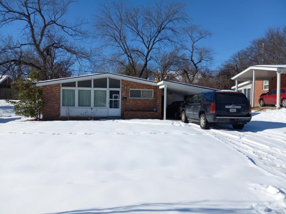 1349 Rushmore Dr, University City, MO 63130 - view of snow covered exterior featuring an attached carport and brick siding