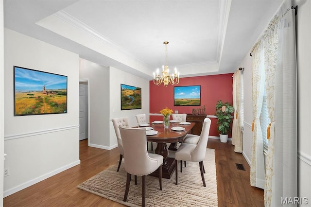 dining room featuring a tray ceiling, a chandelier, wood finished floors, baseboards, and ornamental molding