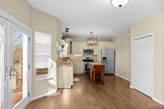 kitchen with stainless steel appliances, baseboards, dark wood-style floors, glass insert cabinets, and decorative backsplash