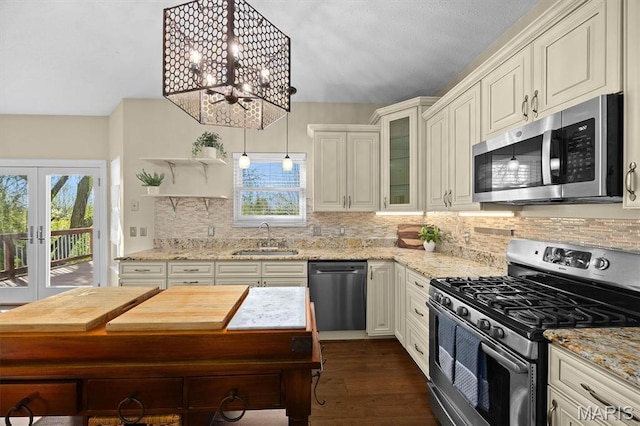 kitchen featuring stainless steel appliances, a sink, plenty of natural light, and light stone countertops