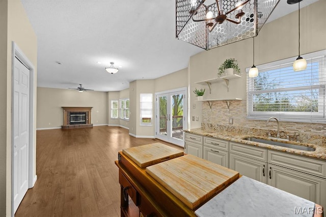 kitchen with a sink, backsplash, baseboards, a chandelier, and wood finished floors
