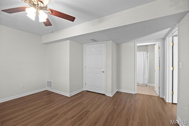 unfurnished bedroom with wood finished floors, baseboards, a ceiling fan, and ensuite bath