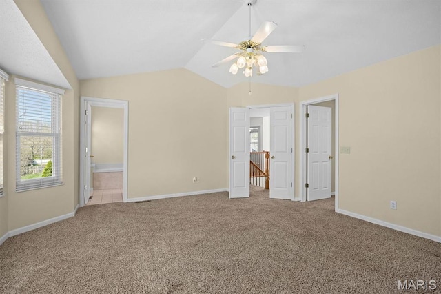 unfurnished bedroom with carpet floors, lofted ceiling, baseboards, ensuite bath, and a ceiling fan