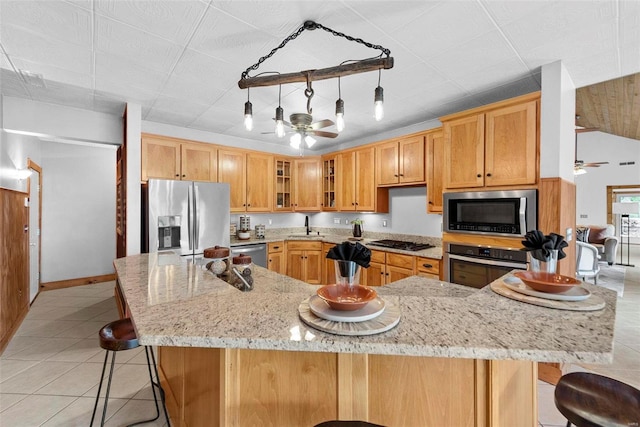 kitchen featuring stainless steel appliances, a ceiling fan, light tile patterned floors, and a kitchen bar