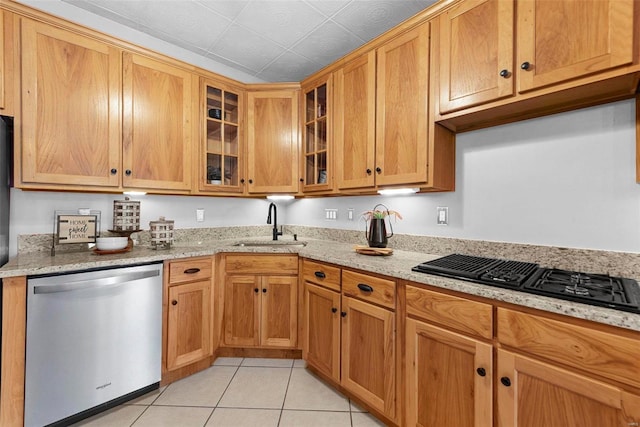 kitchen with dishwasher, black gas cooktop, light tile patterned floors, a sink, and light stone countertops