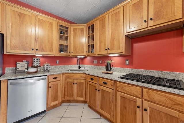 kitchen with stainless steel dishwasher, black gas stovetop, light tile patterned floors, a sink, and glass insert cabinets