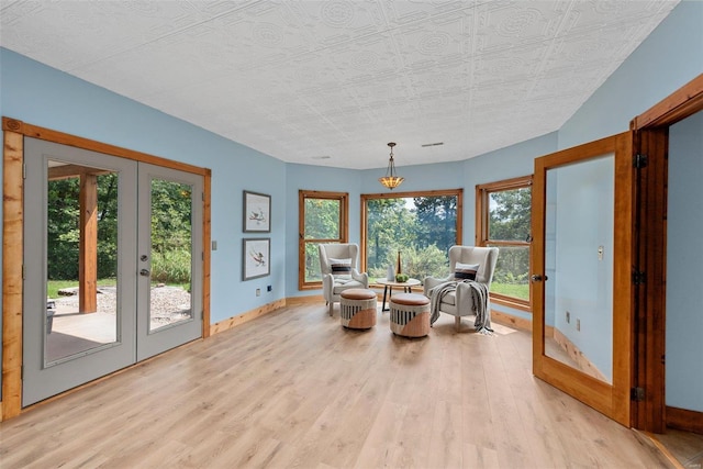 living area featuring french doors, light wood-type flooring, baseboards, and plenty of natural light
