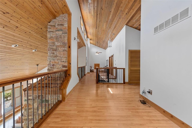 hallway featuring high vaulted ceiling, wood ceiling, wood finished floors, an upstairs landing, and baseboards