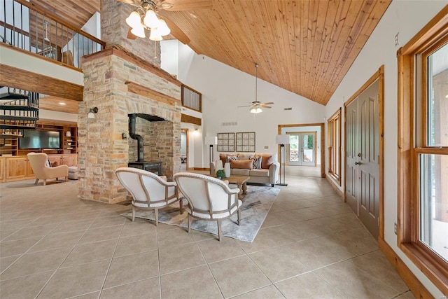 tiled living area featuring ceiling fan, high vaulted ceiling, a wood stove, and wood ceiling