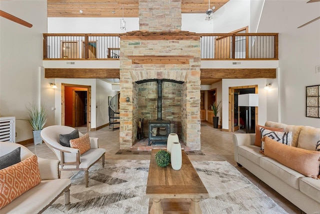 tiled living area with a towering ceiling, baseboards, stairway, a wood stove, and wooden ceiling