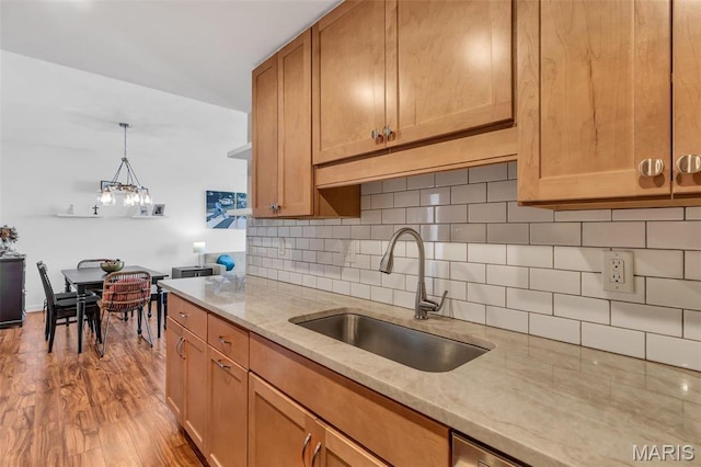 200 S Brentwood Unit 12F, Saint Louis, MO 63105 - kitchen with a sink, light stone counters, decorative backsplash, and wood finished floors