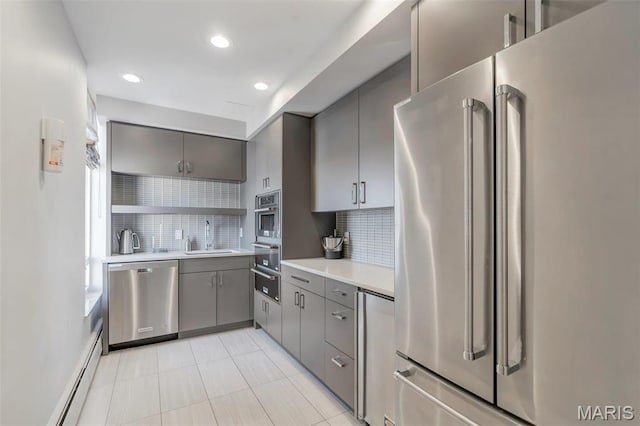200 S Brentwood Unit 12F, Saint Louis, MO 63105 - kitchen with stainless steel appliances, gray cabinets, a baseboard radiator, a warming drawer, and tasteful backsplash