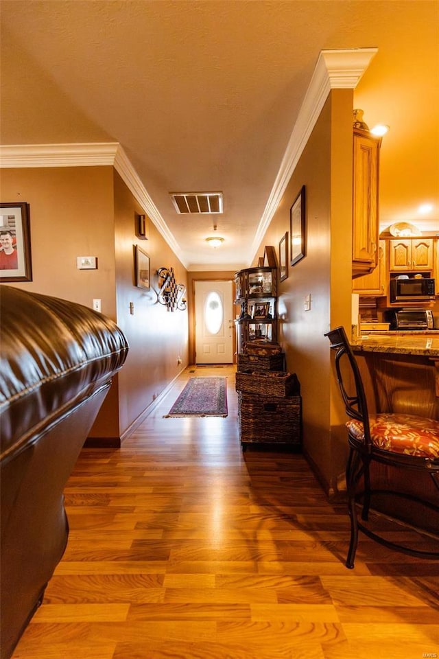 entrance foyer with light wood-style flooring, crown molding, and baseboards