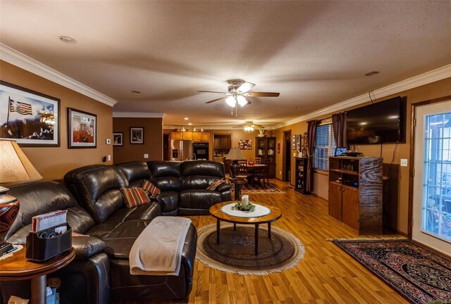 living room with wood finished floors, ceiling fan, and crown molding