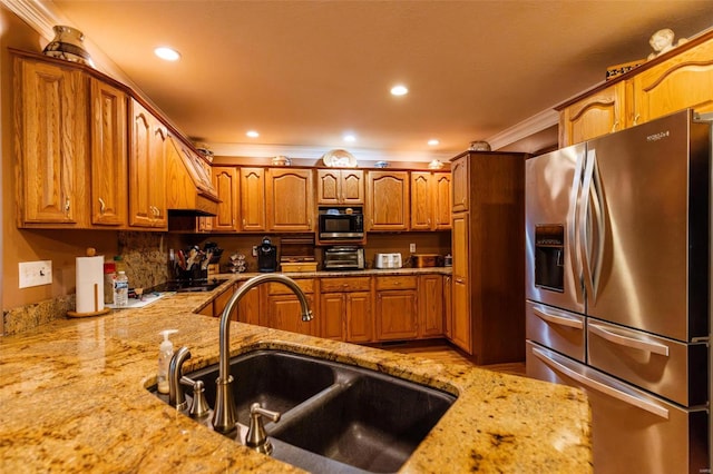kitchen with stainless steel fridge, a sink, light stone counters, brown cabinetry, and crown molding