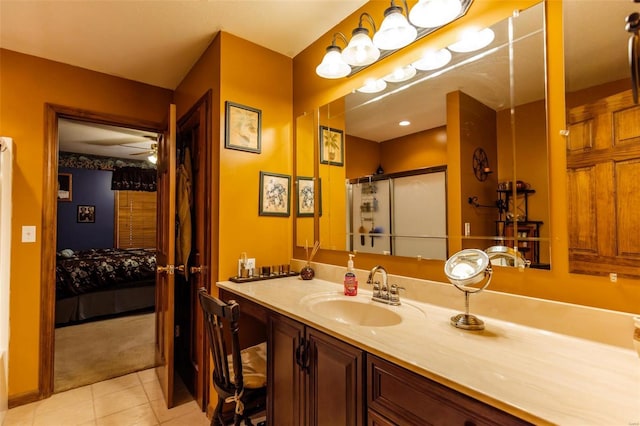 ensuite bathroom with tile patterned floors, a ceiling fan, vanity, and a shower