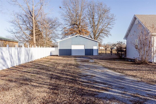 detached garage featuring fence and gravel driveway