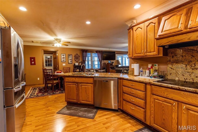 702 S 525th Rd, East Prairie, MO 63845 - kitchen with stainless steel appliances, a peninsula, brown cabinets, ornamental molding, and light wood finished floors