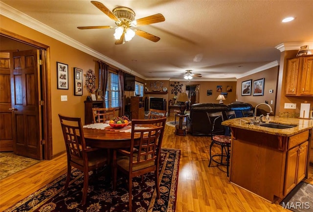702 S 525th Rd, East Prairie, MO 63845 - dining space with ceiling fan, light wood finished floors, ornamental molding, and a fireplace
