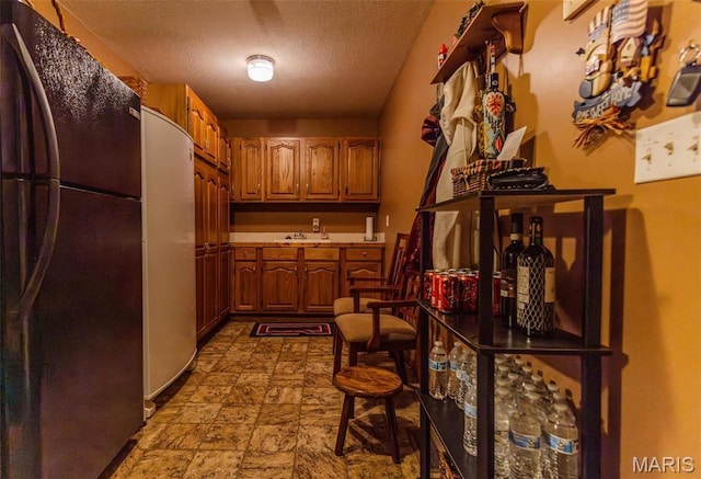 702 S 525th Rd, East Prairie, MO 63845 - interior space with freestanding refrigerator, a sink, brown cabinetry, a textured ceiling, and stainless steel fridge