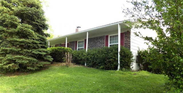 1306 Broadway St, Rolla, MO 65401 - view of property exterior featuring a chimney, a yard, and brick siding