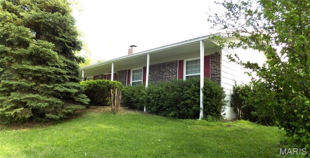 1306 Broadway St, Rolla, MO 65401 - view of side of property with a chimney, a yard, and brick siding