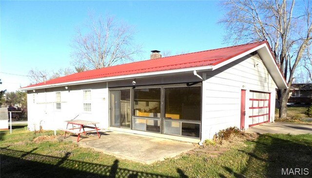 1306 Broadway St, Rolla, MO 65401 - back of property with a chimney, metal roof, a detached garage, and a patio