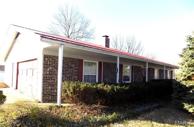 1306 Broadway St, Rolla, MO 65401 - view of property exterior featuring a chimney, brick siding, and an attached garage