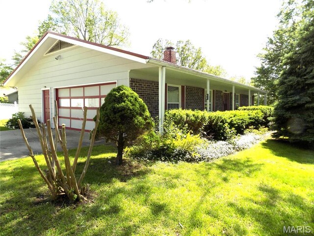 1306 Broadway St, Rolla, MO 65401 - view of side of property featuring a chimney, an attached garage, a lawn, and asphalt driveway