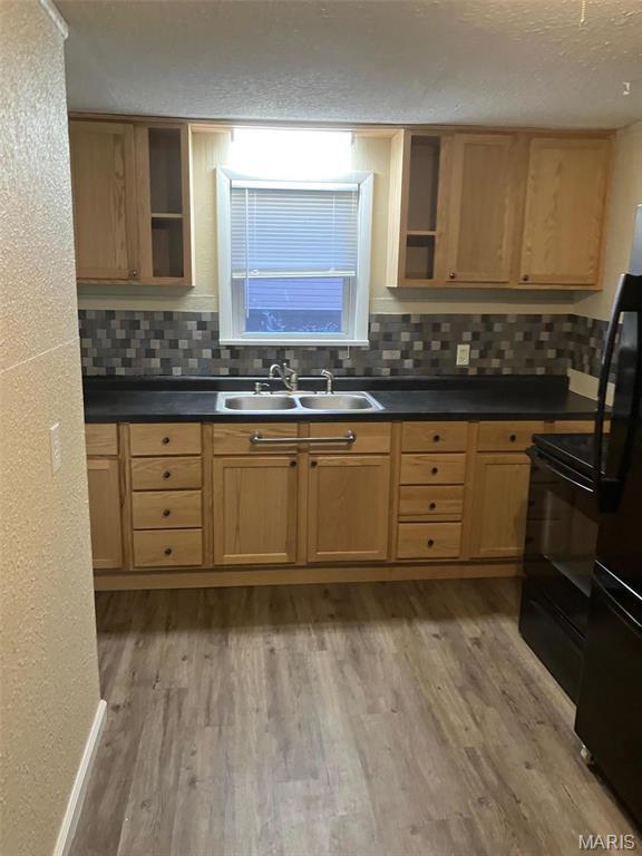 708 E Pear Ave, Owensville, MO 65066 - kitchen featuring a sink, open shelves, decorative backsplash, black appliances, and light wood-style floors