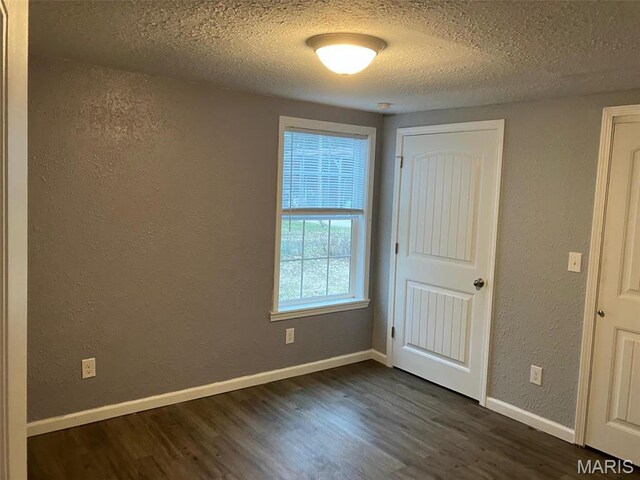 708 E Pear Ave, Owensville, MO 65066 - unfurnished bedroom featuring a textured wall, dark wood-style floors, a textured ceiling, and baseboards