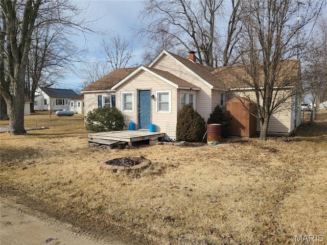 708 E Pear Ave, Owensville, MO 65066 - view of front of house with a shed, a chimney, an outdoor fire pit, an outbuilding, and a front lawn