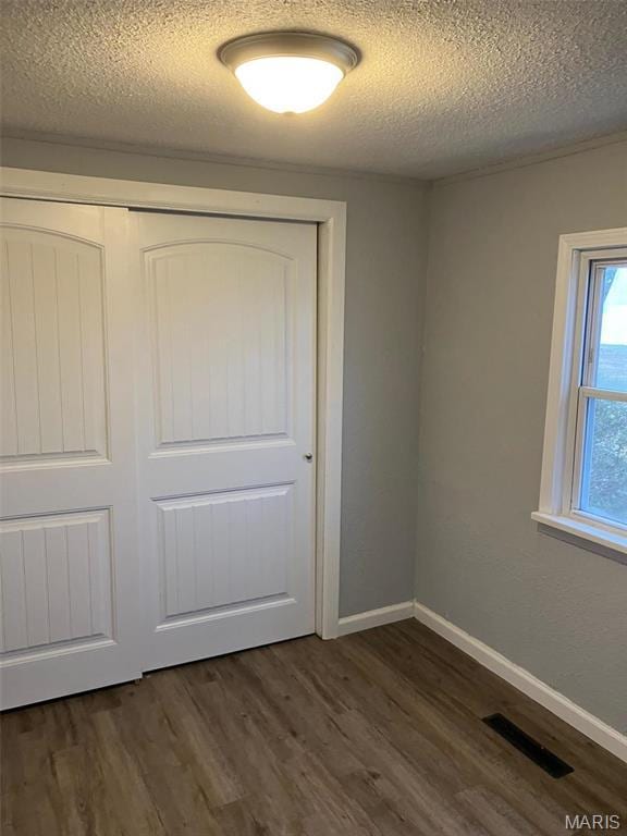 708 E Pear Ave, Owensville, MO 65066 - unfurnished bedroom featuring a textured ceiling, dark wood-type flooring, a closet, and baseboards