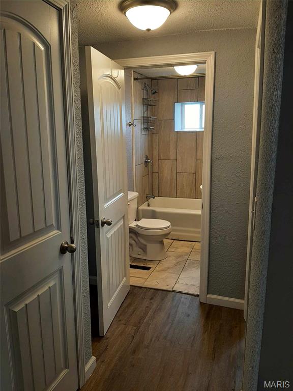 708 E Pear Ave, Owensville, MO 65066 - bathroom with toilet, wood finished floors, a textured wall, tub / shower combination, and a textured ceiling