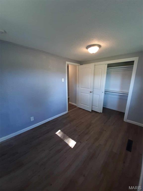 708 E Pear Ave, Owensville, MO 65066 - unfurnished bedroom featuring baseboards, dark wood-type flooring, and a closet