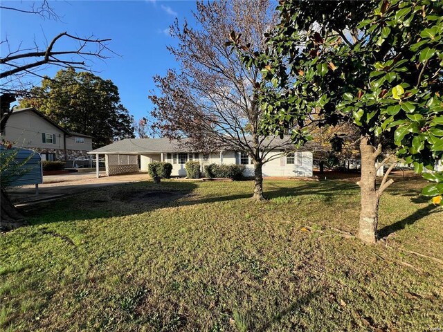 view of green lawn with an attached carport